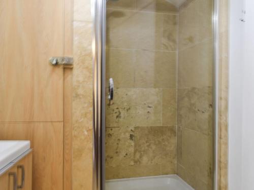 een douche met een glazen deur in de badkamer bij Byways in Cartmel