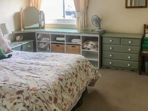 a bedroom with a bed and a dresser with a mirror at Harbour Cottage in Millom
