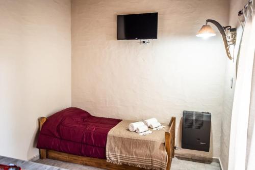a bedroom with a red bed and a tv on the wall at El Campo in Sierra de la Ventana