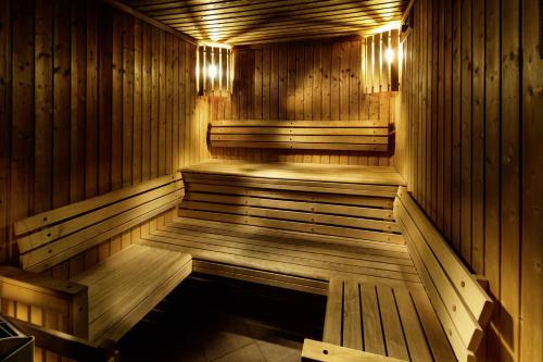 a wooden sauna with benches and lights in it at pentahotel Paris Charles de Gaulle in Roissy-en-France