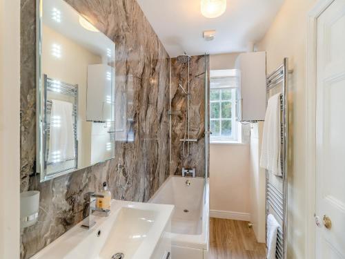 een badkamer met een wastafel, een bad en een spiegel bij Crag View in Ambleside