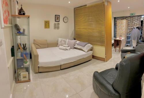 een slaapkamer met een bed, een bank en een stoel bij Home2home in Hendon