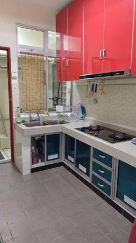 a kitchen with red cabinets and a counter top at Rumahku in Kota Kinabalu
