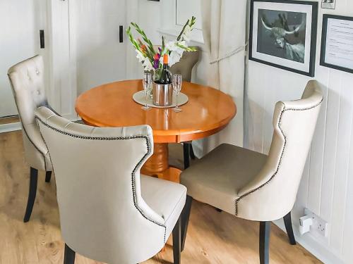 uma mesa de madeira com duas cadeiras e uma mesa com flores em Harperfield Chalet em Lanark