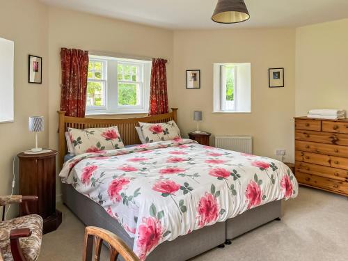 a bedroom with a bed with a floral comforter at Dairy Cottage in Whitehouse