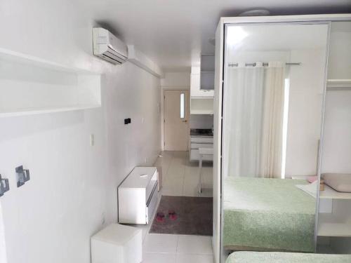une chambre blanche avec une porte en verre menant à une chambre dans l'établissement 1/4 na praia de Armação, à Salvador