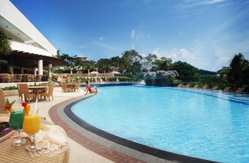 a pool at a resort with tables and chairs at Marco Polo Plaza Cebu in Cebu City