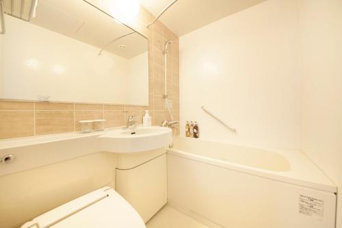 a bathroom with a sink and a toilet and a tub at Richmond Hotel Sapporo Ekimae in Sapporo
