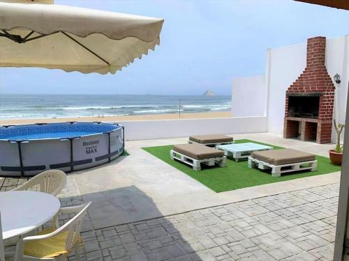 Magnífica Casa de playa 3BR في لورين: فناء مع طاولة ومدفأة والشاطئ