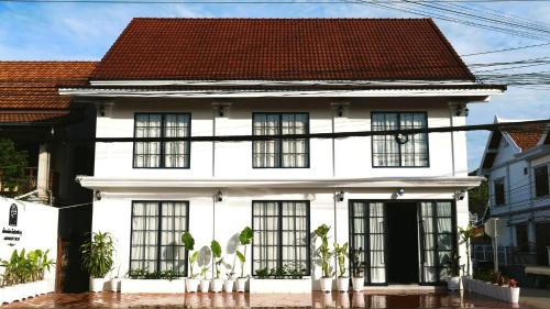 ein weißes Haus mit schwarzen Fenstern und einem roten Dach in der Unterkunft Midnight Blue Guesthouse in Luang Prabang