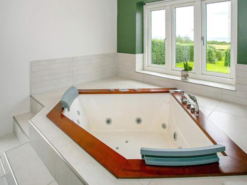 Holiday home Asperup V في Asperup: حوض استحمام في حمام مع نافذتين
