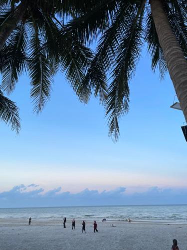 a group of people on a beach with a palm tree at Homestay Husna in Dungun