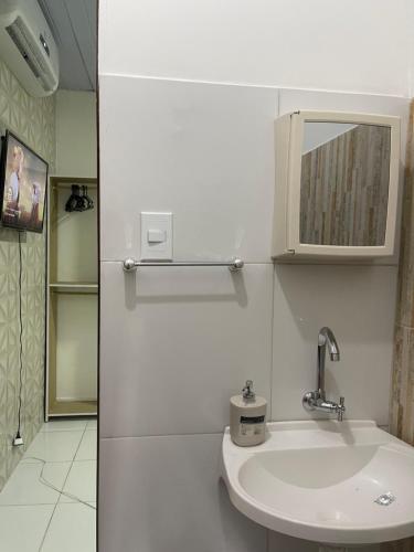La salle de bains blanche est pourvue d'un lavabo et d'un miroir. dans l'établissement Napolitan House, à Manaus