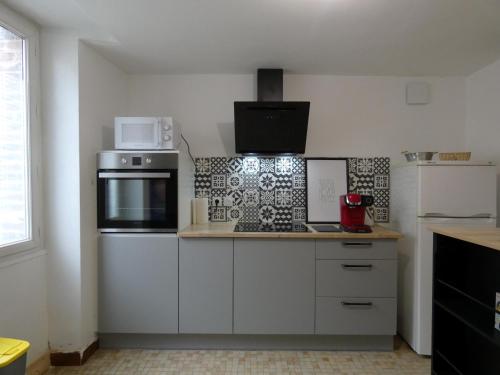 une cuisine avec des armoires blanches et un four à plaques de cuisson dans l'établissement Élégante maison de ville avec cour intérieure, centre de Châteaudun, proche sites touristiques - FR-1-581-115, à Châteaudun