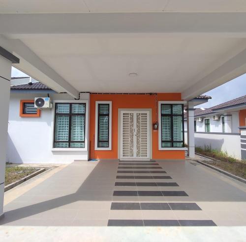 an empty house with an orange door and a checkered floor at LOMPOI HOMESTAY Islam Guest in Merlimau