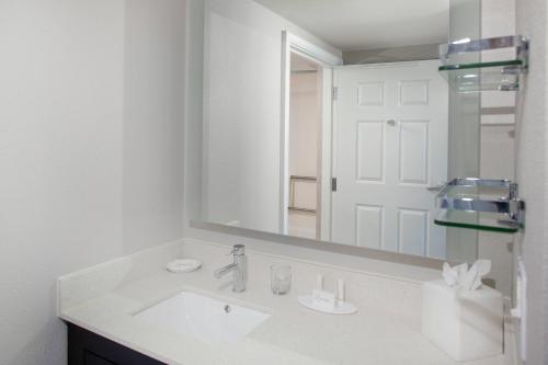 Baño blanco con lavabo y espejo en Residence Inn By Marriott Virginia Beach Oceanfront en Virginia Beach