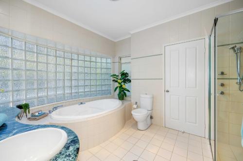 a bathroom with a tub and a toilet and a sink at Paradise View @ Bonny Hills in Bonny Hills