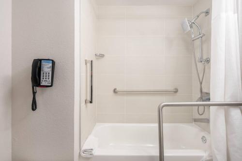 Fairfield Inn and Suites by Marriott Palm Beach في بالم بيتش: حمام مع هاتف بجانب حوض الاستحمام
