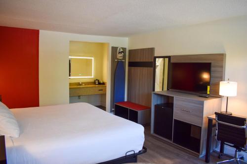 a hotel room with a bed and a flat screen tv at Ramada by Wyndham Cleveland Airport West in Fairview Park