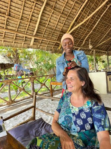 a woman getting her hair cut by a woman at Juani beach bungalows in Kilindoni