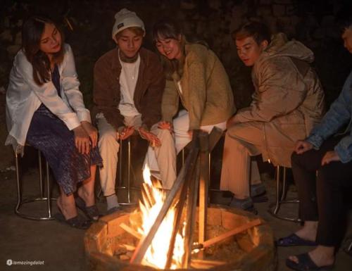 Eine Gruppe von Menschen, die um ein Feuer herum sitzen in der Unterkunft Nhà của Sóc in Da Lat