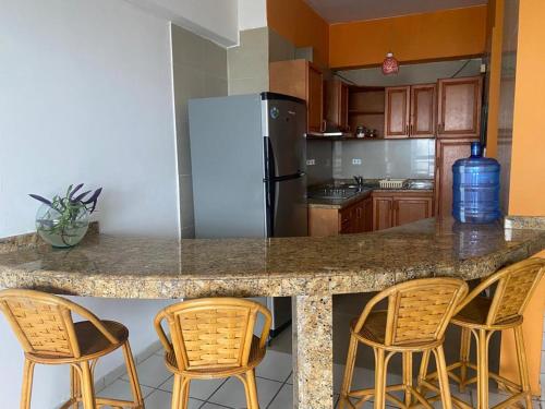 a kitchen with a counter with chairs and a refrigerator at Apartamento Vista al Mar in Porlamar