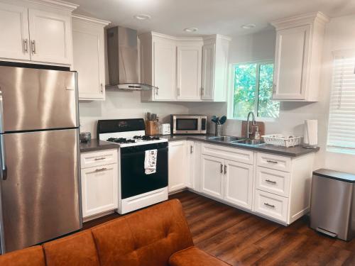 a kitchen with white cabinets and a stainless steel refrigerator at Farmhouse Near Disneyland and Old Town Orange in Orange