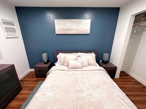 a bedroom with a large bed with a blue wall at Farmhouse Near Disneyland and Old Town Orange in Orange