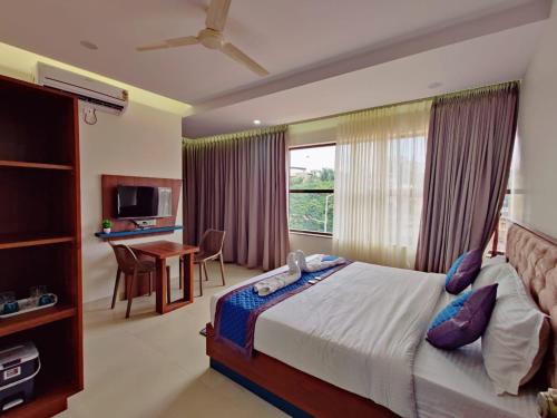 a bedroom with a bed and a desk and a window at Hotel Royal Inn Lodge Dharwad in Dhārwād