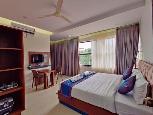 a bedroom with a bed and a desk and a window at Hotel Royal Inn Lodge Dharwad in Dhārwād