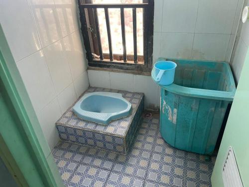 a bathroom with a blue toilet and a trash can at SPOT ON 93037 Nova Jaya Homestay Syariah in Lamongan