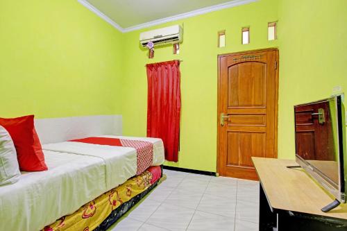 Schlafzimmer mit einem Bett, einem TV und einer Tür in der Unterkunft OYO 92998 Wiludjeng Guesthouse in Sragen