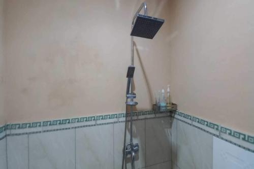 a shower in a bathroom with a hose on the wall at OYO 93011 Hotel Griya Lestari Pati 2 in Pati