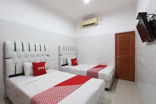 a bedroom with two beds with red and white sheets at OYO 93011 Hotel Griya Lestari Pati 2 in Pati