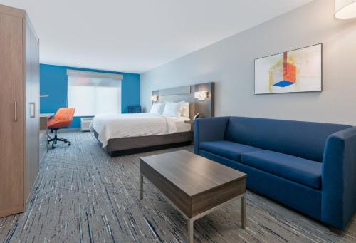 Habitación de hotel con cama y sofá azul en Holiday Inn Express Hotel & Suites Shakopee, an IHG Hotel en Shakopee