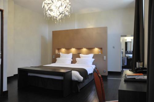 a bedroom with a large bed and a chandelier at Château de Champlong Table Hôtel **** Golf & Spa in Villerest