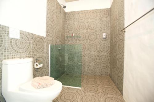a bathroom with a toilet and a glass shower at Lime N Soda Beachfront Resort in Thongsala