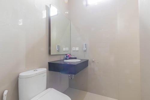 a bathroom with a toilet and a sink and a mirror at Mandhasativa Homestay in Singaraja