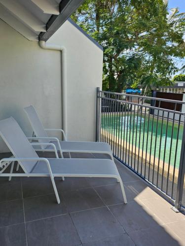 two chairs sitting on a porch with a fence at Airlie Seaview Apartments in Airlie Beach