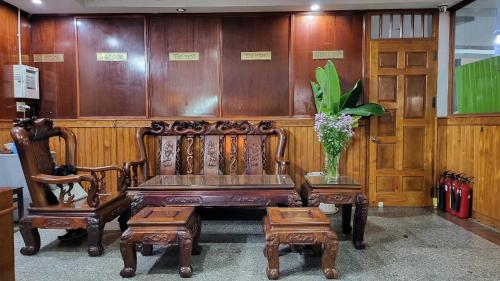 eine Holzbank mit zwei Stühlen und einer Vase aus Blumen in der Unterkunft Khách Sạn Phương Lâm in Dồng Xoài