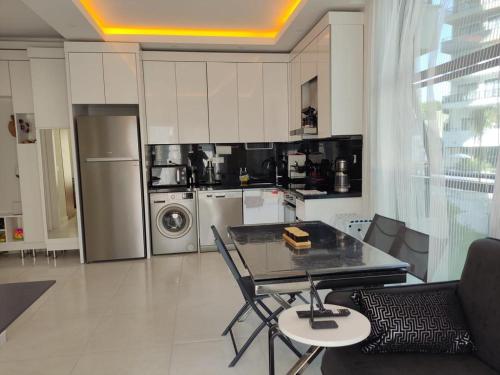 uma sala de estar com uma mesa e uma cozinha em Квартира в прекрасном комплексе em Mahmutlar