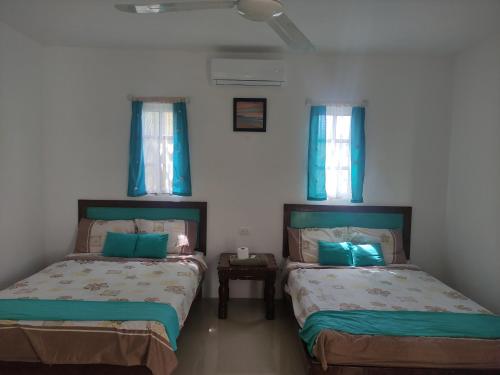 two beds in a room with blue windows at Departamentos y habitaciones Sak Naj in Telchac Puerto