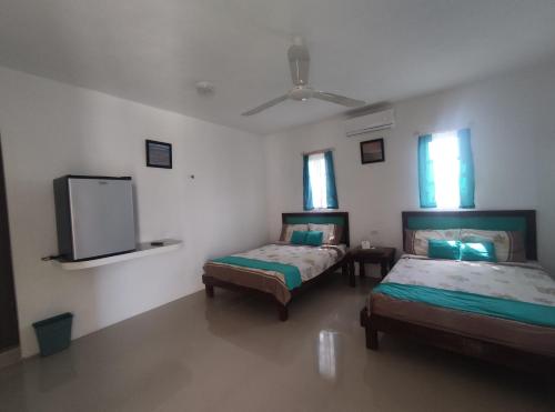 a room with two beds and a flat screen tv at Departamentos y habitaciones Sak Naj in Telchac Puerto