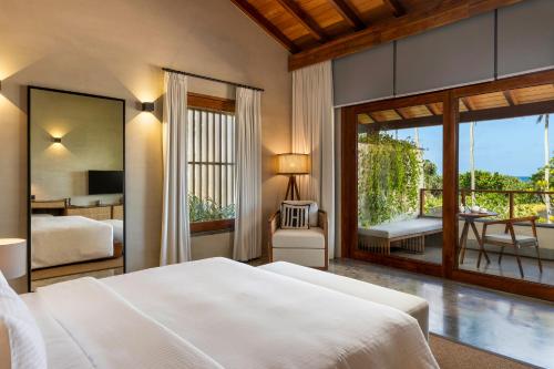 a bedroom with a bed and a balcony with a table at Villa Thamburu, Bentota in Bentota