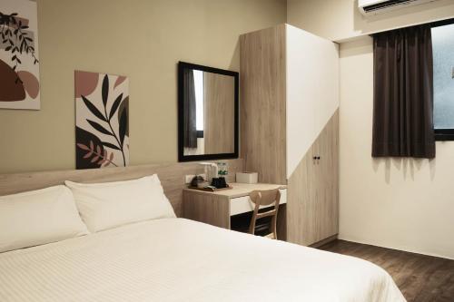1 dormitorio con cama y escritorio con espejo en Jincheng Hostel, en Changhua County