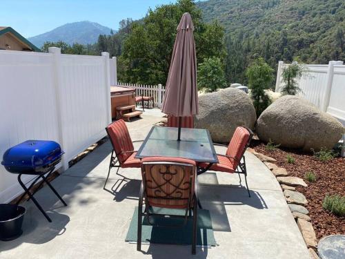 a patio with a table and chairs and an umbrella at Eagle Nest River Views Hot Tub Games Sleeps 6 in Ahwahnee