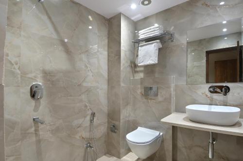 a bathroom with a toilet and a sink and a shower at The Saina International Delhi - By La Exito Hotels in New Delhi