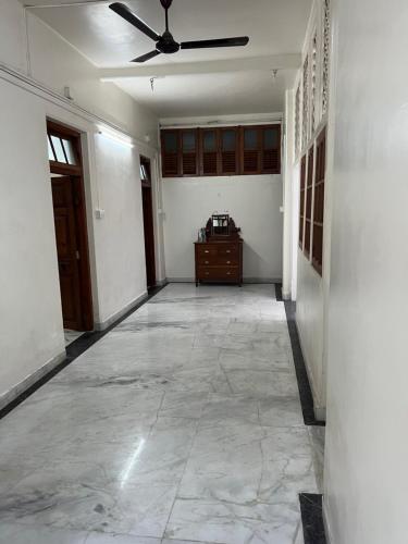 an empty room with a ceiling fan and a hallway at Hotel Laxminarayan Niwas in Pune
