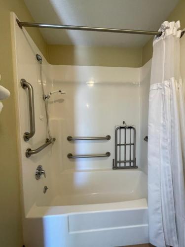 a bathroom with a tub and a shower with a shower curtain at Howard Johnson by Wyndham Ridgecrest, CA in Ridgecrest