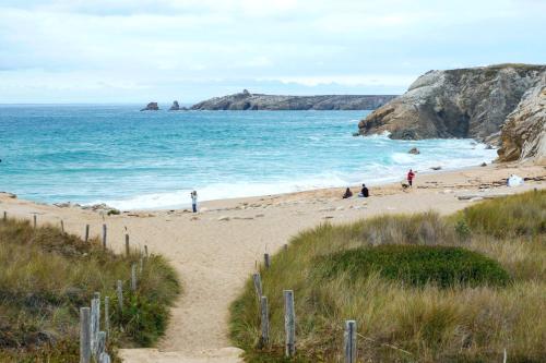 a beach with people on the sand and the ocean at Appart'Hôtel & Spa "Les Voiles" Le Houat in Carnac